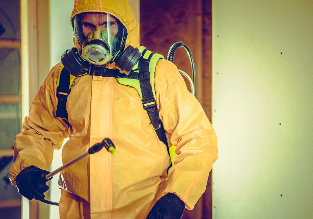Odor removal technician spraying deodorizer in hazmat gear